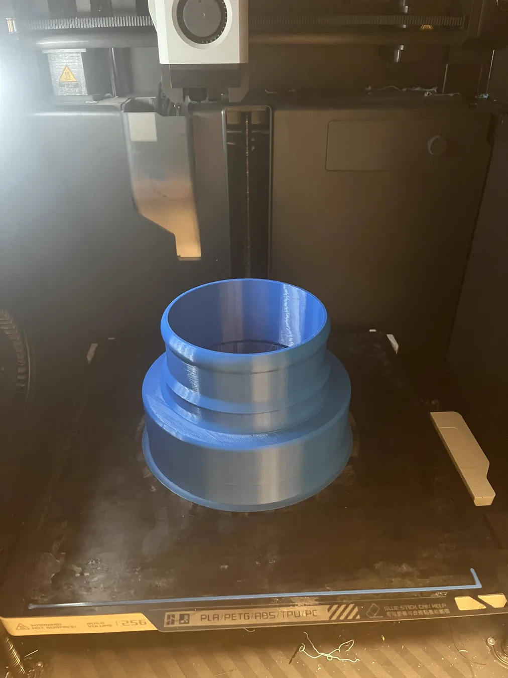 Blue 3D-printed engine air-filter adapter on a printer bed
