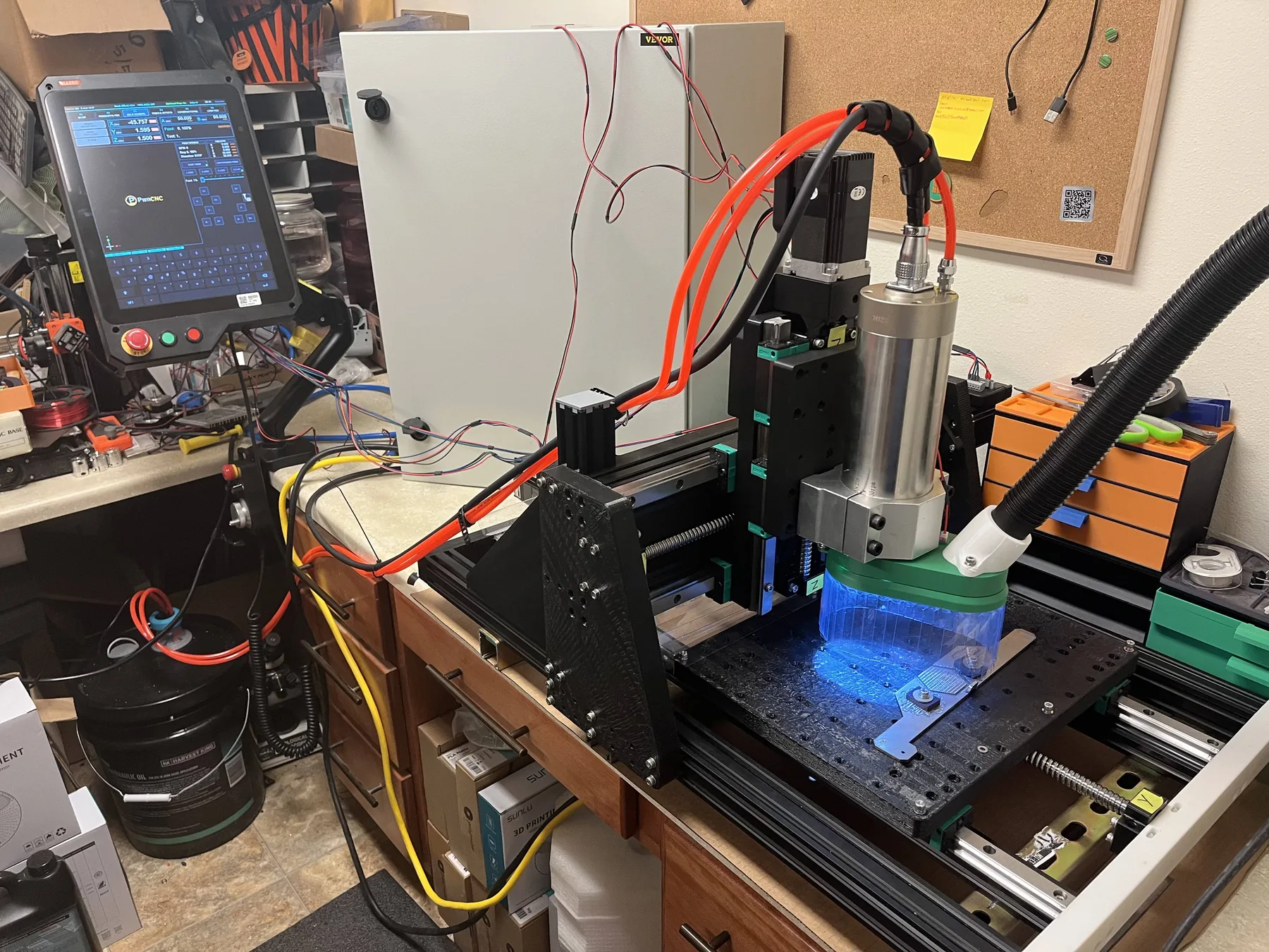 Desktop CNC mill operating with blue work lighting